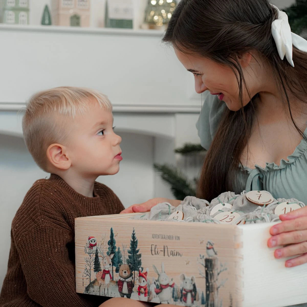 Kind mit Mutter und Adventskalender in der Hand. Weihnachtsüberraschung