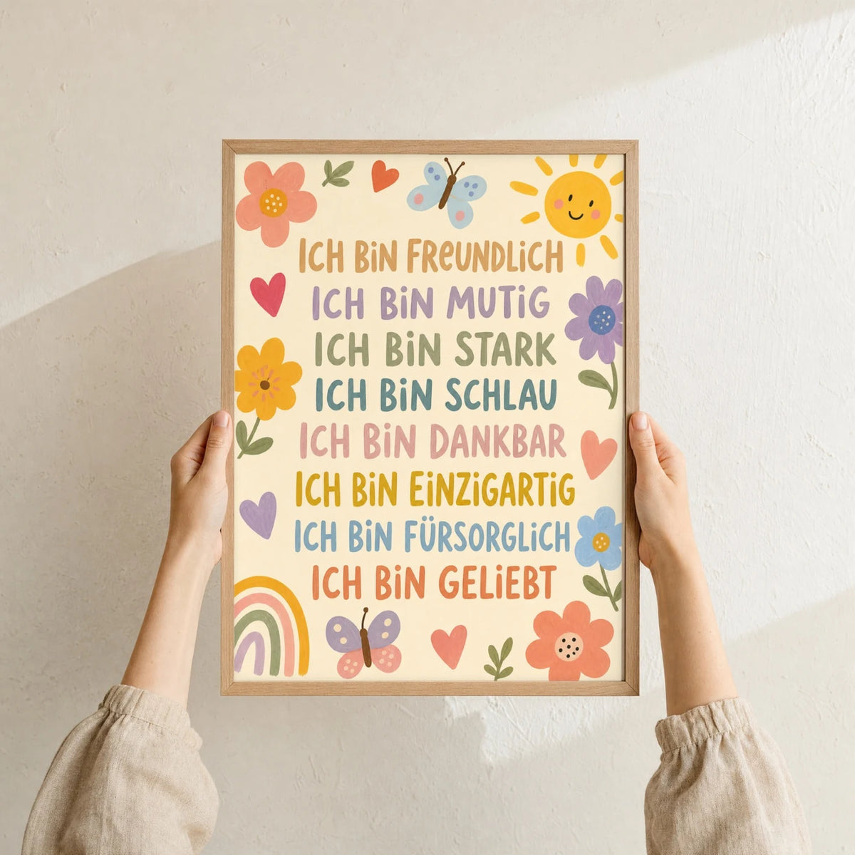 Affirmationsposter âBlumenwiese Ich bin freundlichâ im Holzrahmen in den HĂ€nden gehalten â Taufgeschenk und Kinderzimmer Deko