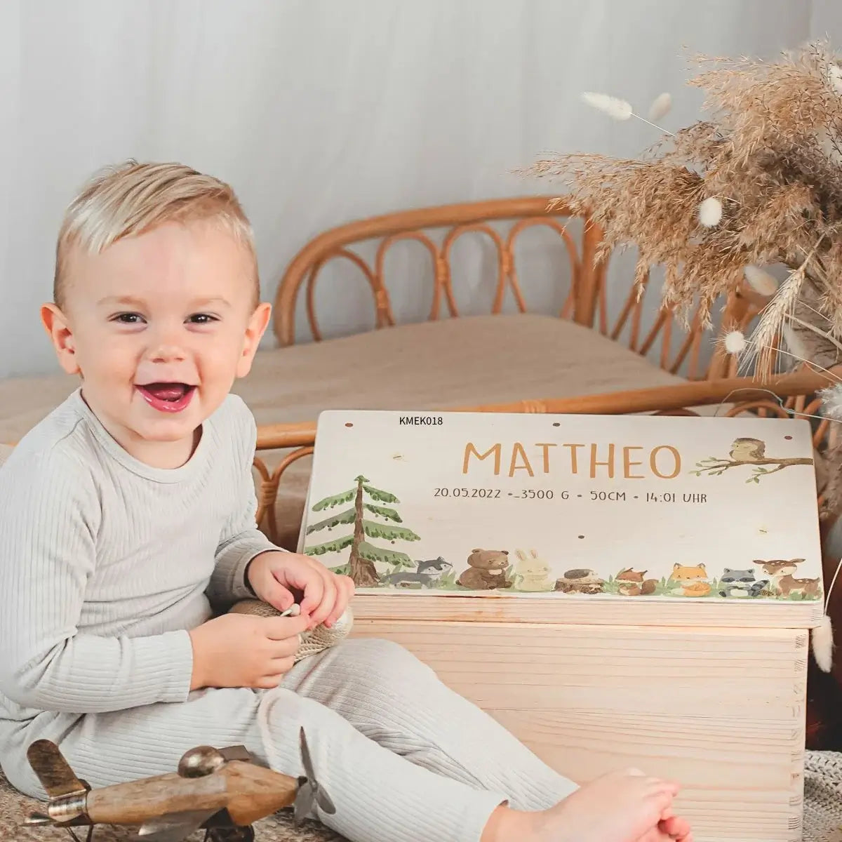 Personalisierte Erinnerungsbox aus Holz mit Namen Mattheo und Geburtsdaten, Waldtier-Motiv, Kind zeigt Freude ĂĽber personalisiertes Geschenk zur Geburt