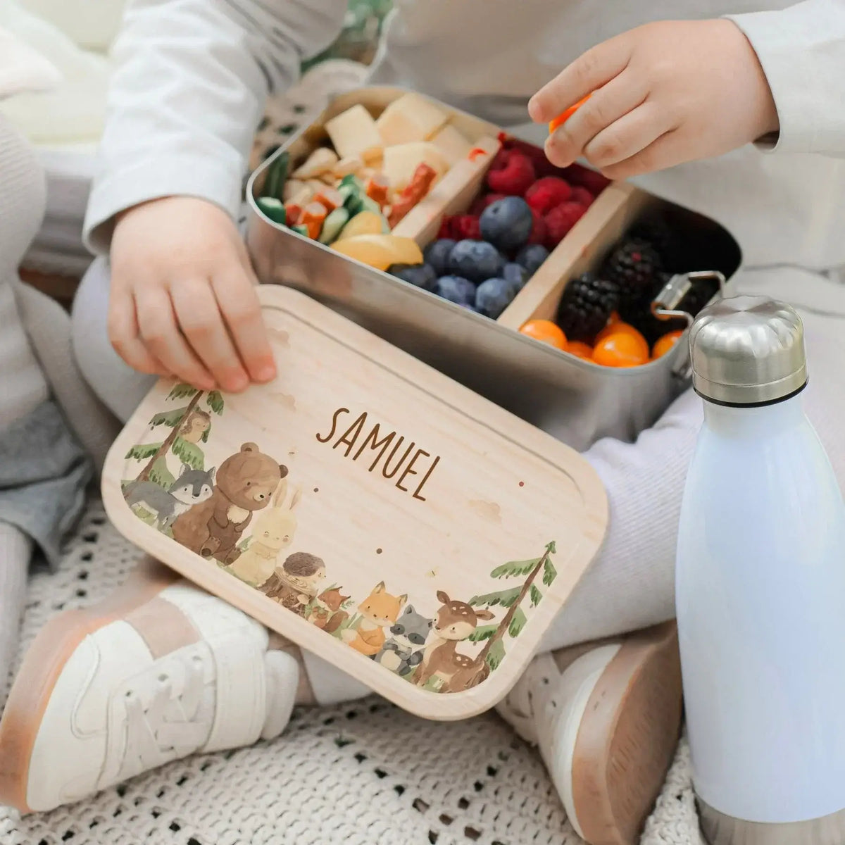 Kind isst auf Boden mit Lunchbox gesundes Obst
