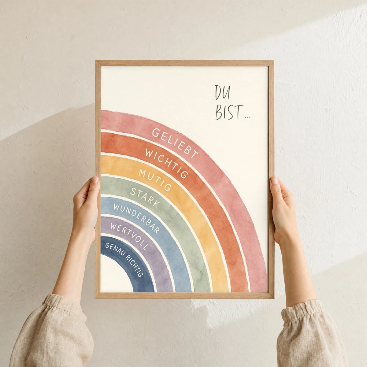 Affirmationsposter „Regenbogen Du bist“ im Holzrahmen in den Händen gehalten – Taufgeschenk und Kinderzimmer Deko